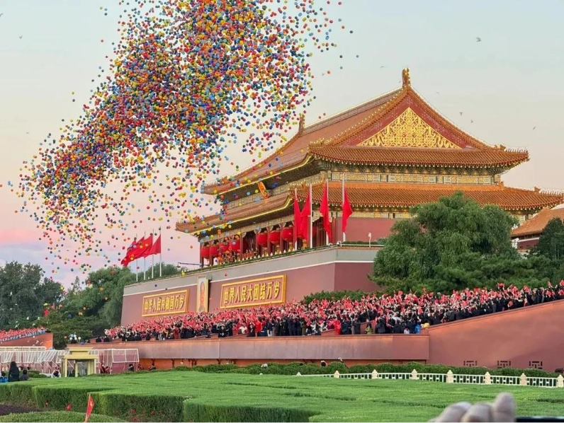 Em frente a um palácio dourado na China, multidão celebra com bandeiras vermelhas enquanto milhares de balões coloridos sobem ao céu durante a Golden Week na China.